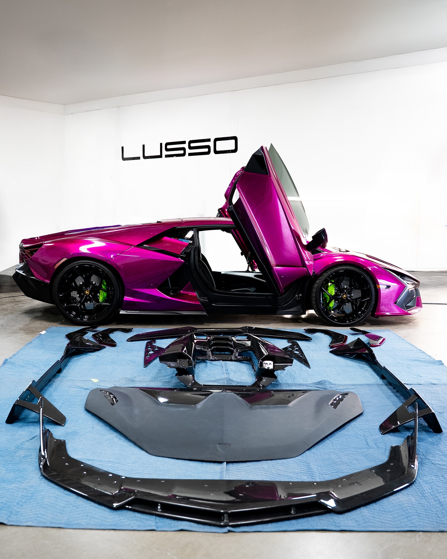 Carbon aero kit components staged next to a Lamborghini Revuelto