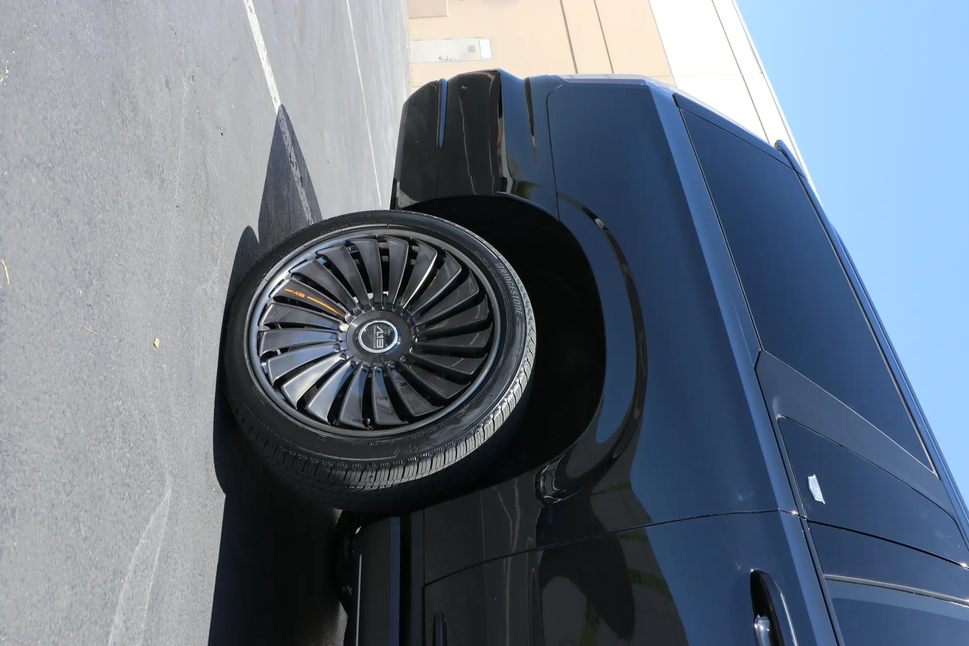 Custom multi-spoke wheel and tire fitted to a black vehicle by Lusso Auto Design