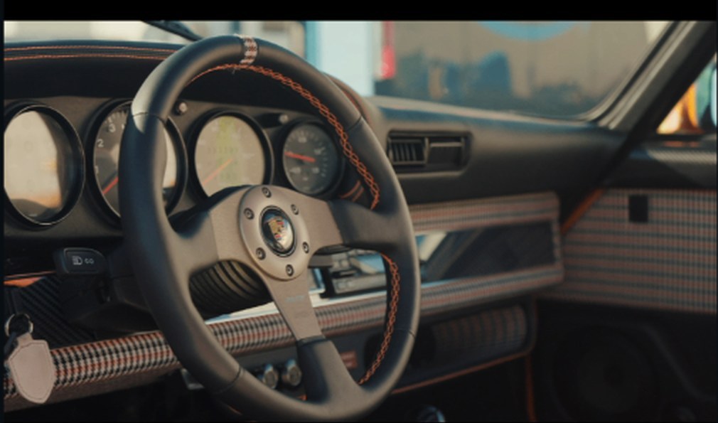 Momo Prototipo steering wheel with houndstooth and orange-stitched dash behind